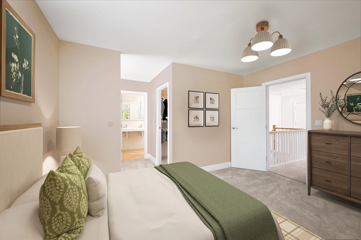 Well-decorated bedroom with a bed featuring green pillows and blanket, a nightstand with a lamp, and a framed floral picture above the headboard. Beige walls and carpeted flooring, with a wooden dresser on the right topped with a round mirror and plants. Two doorways lead to an en-suite bathroom and another room, with three pendant lights hanging from the ceiling.