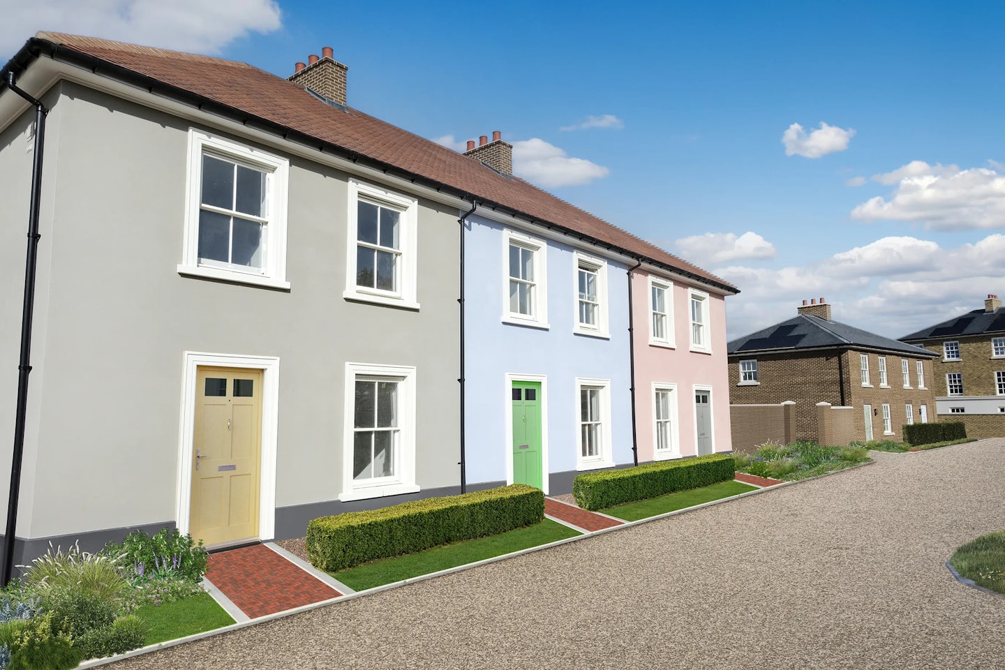 Three two-story terraced houses with light gray, blue, and pink facades, each with white-framed windows and distinctively colored doors, fronted by small gardens and red brick paths, under a blue sky with scattered clouds.
