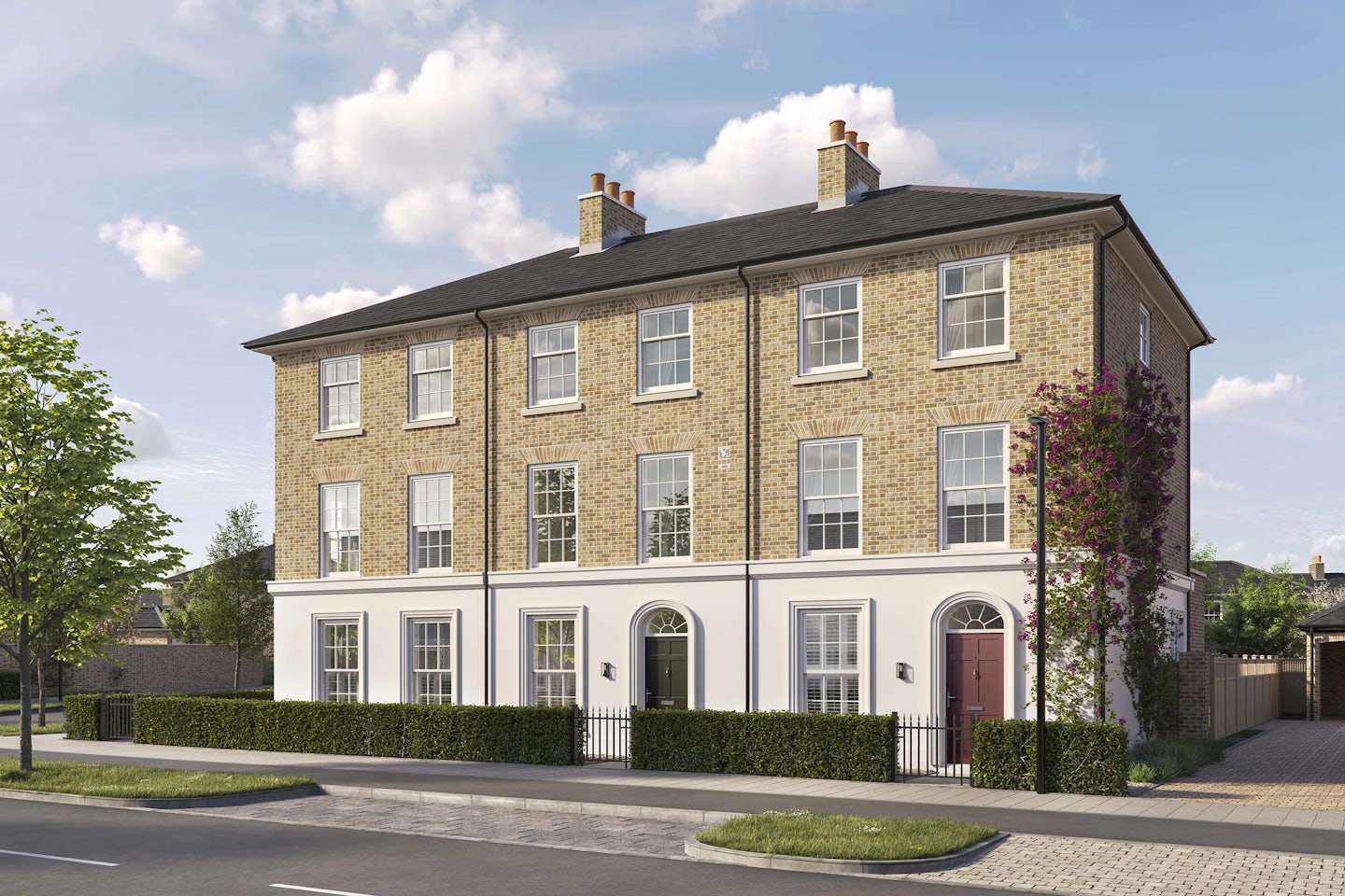 Three-story brick townhouse with a pitched roof and white-framed sash windows. The ground floor features a white-painted facade with three arched doorways, two with black doors and one with a red door. Low hedges and black railings border the front of the property, and a tall flowering vine climbs the right side of the building. The house is situated on a paved street with a young tree in the foreground under a bright blue sky with scattered clouds.