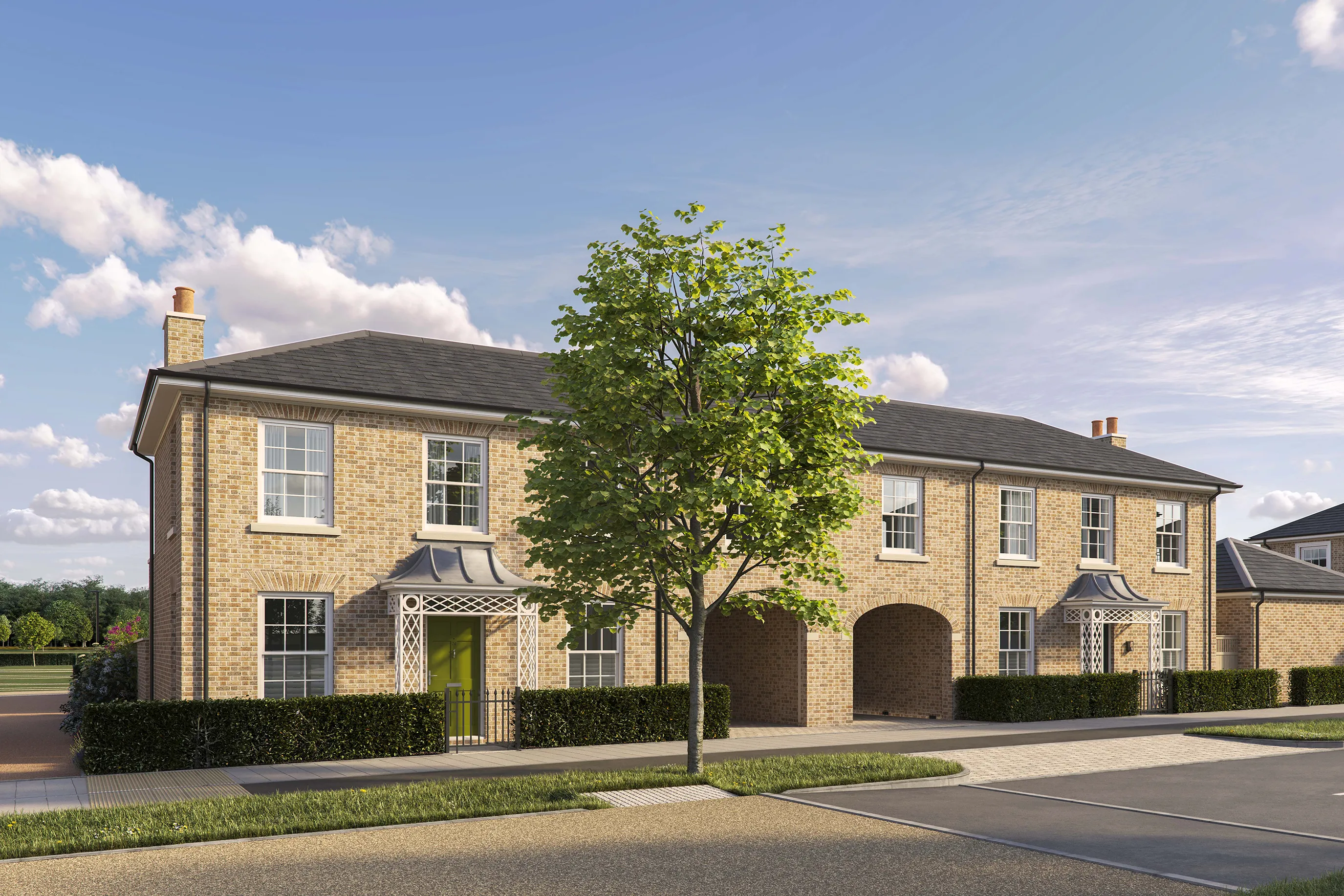 Two-story semi-detached brick houses with pitched roofs and white-framed sash windows. Each house has a front door with a decorative canopy, one painted green and the other partially visible on the right. The property includes two large arched carport openings in the center. A low hedge runs along the front, and a tree is planted on the pavement in the foreground. The sky is bright blue with scattered clouds.