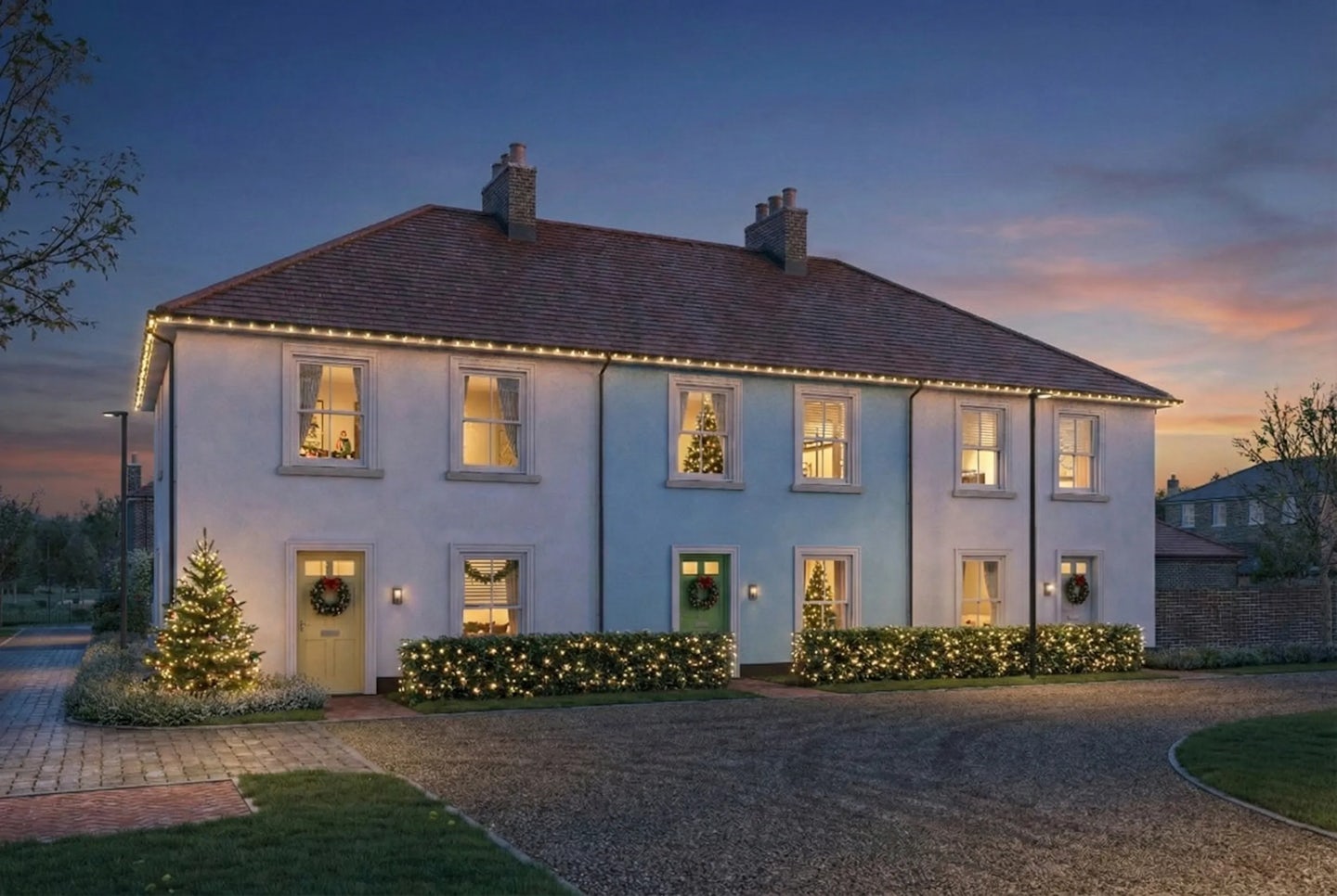 Two-story semi-detached house decorated for Christmas with warm white lights along the roofline, wreaths on the doors, and illuminated shrubs and trees in the front garden. The photo is taken at dusk with a clear sky.