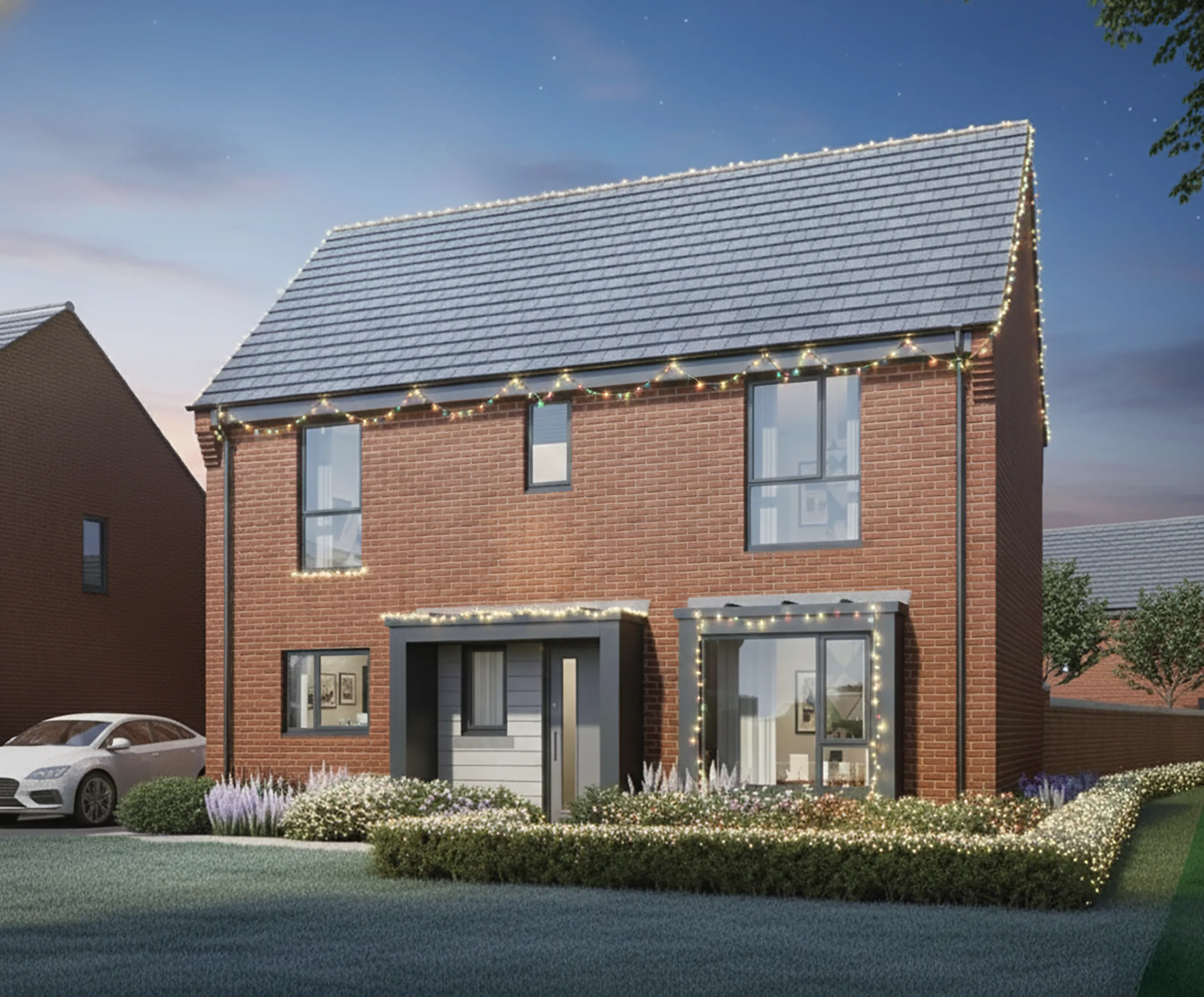 Two-story red-brick house with a pitched gray roof, decorated for Christmas with warm white lights along the roofline and above the porch. The property features large windows, landscaped shrubs, and a paved driveway with a white car parked to the side, photographed at dusk under a clear sky.