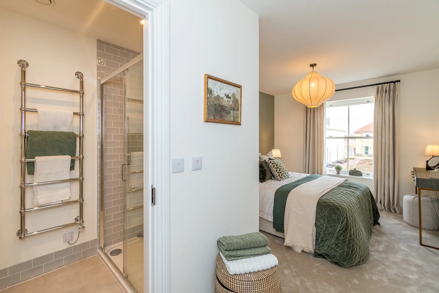A bedroom with a double bed, green bedding, bedside tables, and an open doorway to an en‑suite shower room.