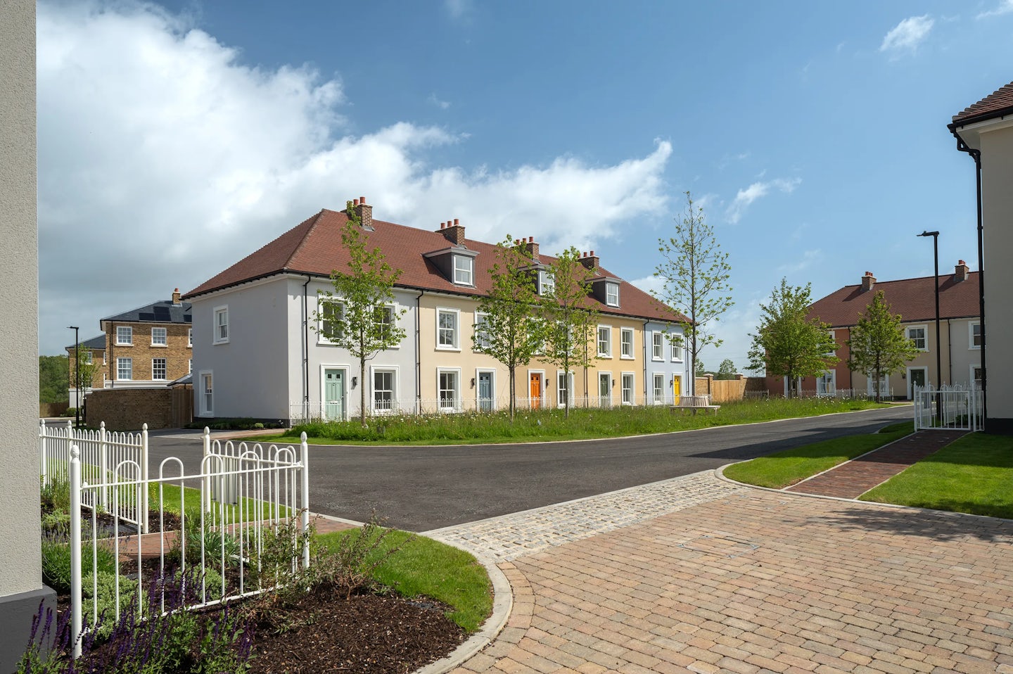 Detached and semi-detached brick houses along a curved residential street with a small front garden and a brick wall