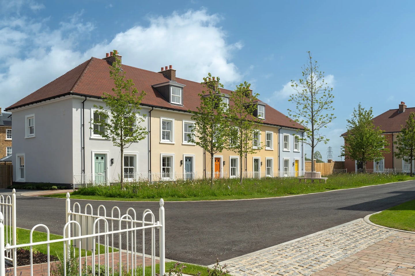 Detached and semi-detached brick houses along a curved residential street with a small front garden and a brick wall