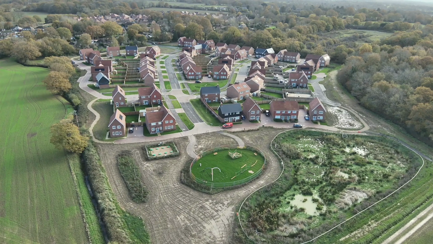 Aerial view highlighting a neighbourhood park with play equipment and open green space next to newly built homes.