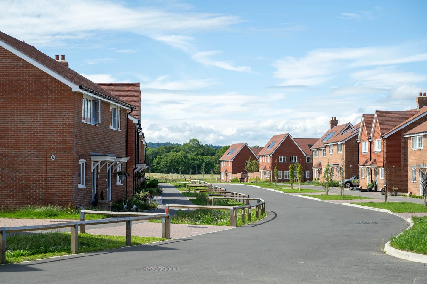Street view of modern brick homes with low timber railings and footpaths leading to front doors