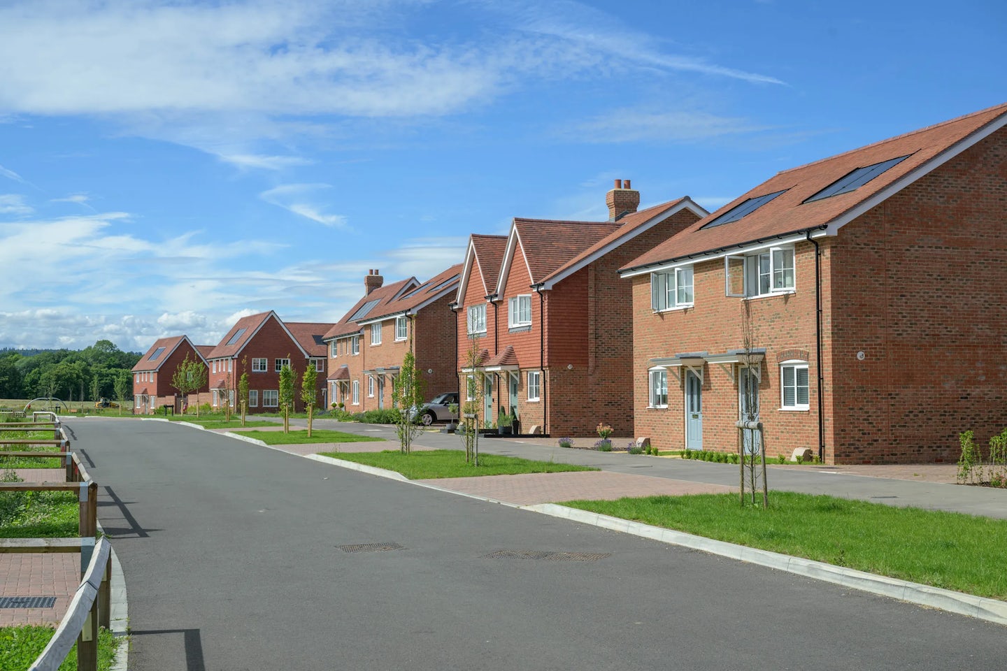Row of new brick houses along a quiet residential street with driveways and small front gardens