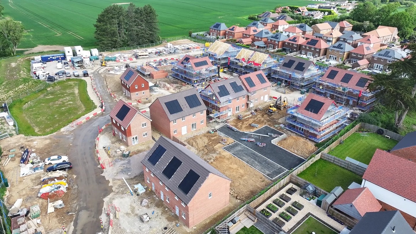 Close aerial view of new brick houses under construction with solar panels and unfinished roads
