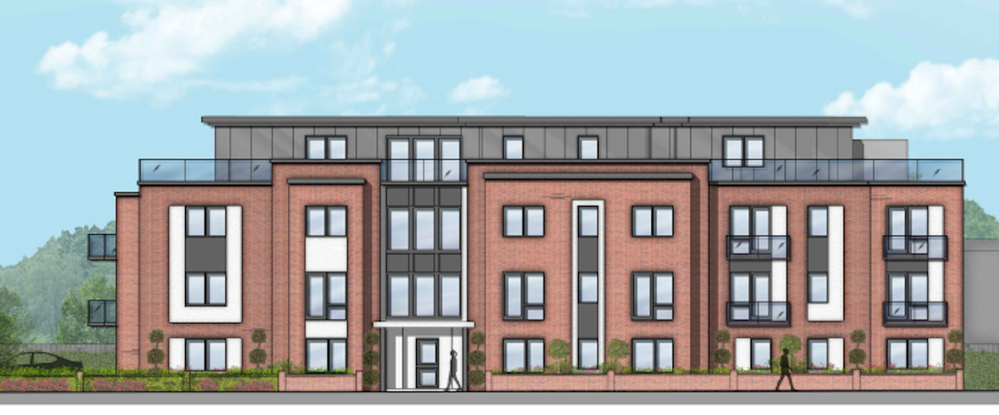 Proposed three-storey apartment building at Station Road, Chertsey, featuring a red brick façade with dark metal cladding at roof level. The building includes large windows, private balconies and a central entrance, with landscaping and pedestrian walkways along the frontage.