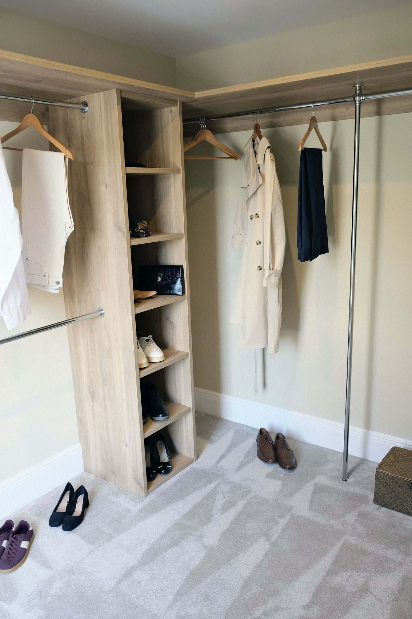 Walk-in wardrobe with open shelving, hanging rails, shoes and clothing neatly displayed, and soft carpet flooring.