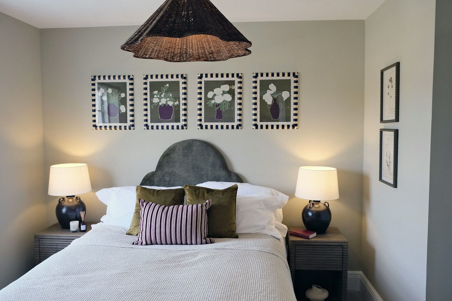 Elegant bedroom with a double bed, upholstered headboard, matching bedside lamps, framed floral artwork, and neutral décor.