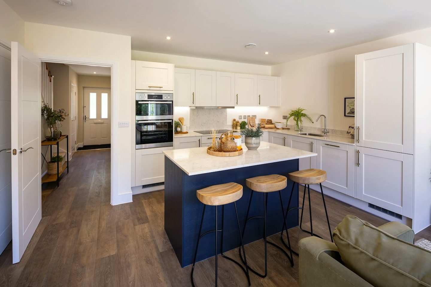 Modern kitchen with white shaker-style cabinets, integrated appliances, quartz-effect worktops, and a central island.