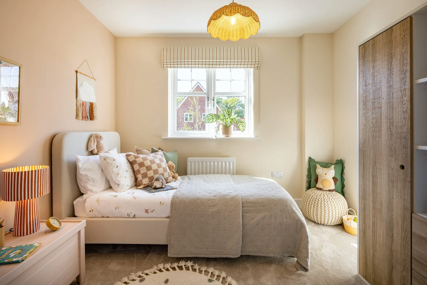 Children's bedroom with a single bed, neutral décor, soft furnishings, bedside table, and window with natural light.