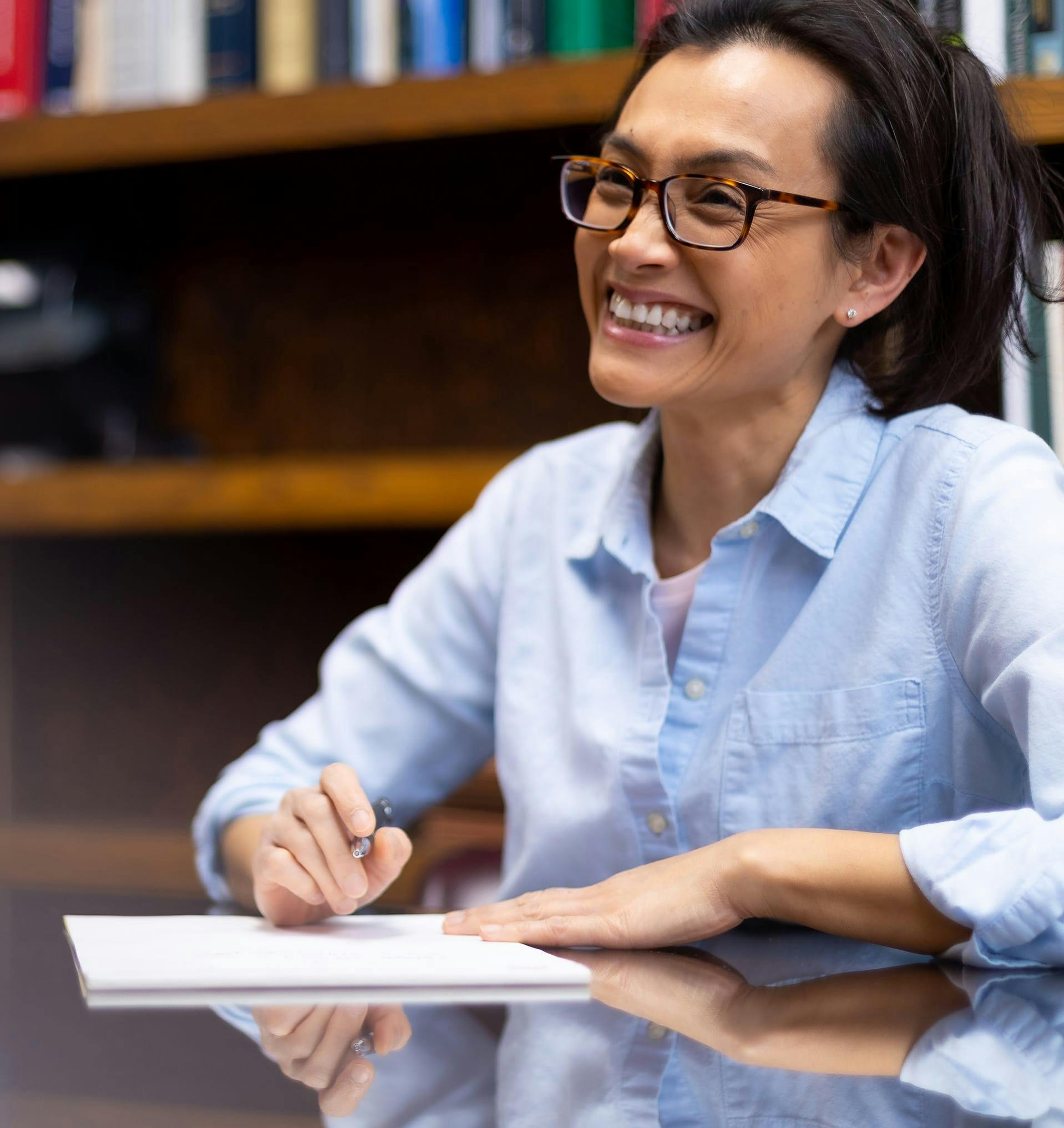 Smiling woman signing a paper.