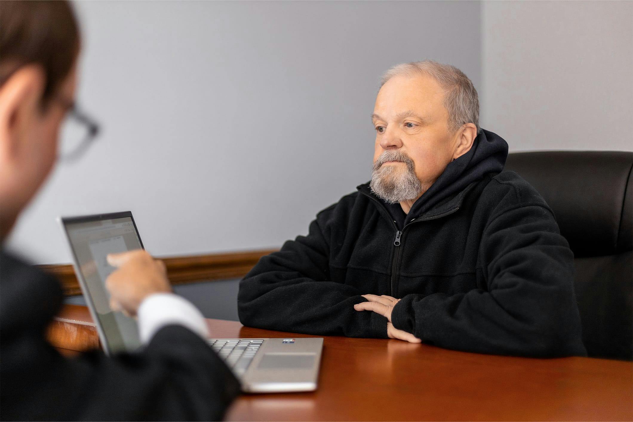 Man sitting across a desk reading a computer.