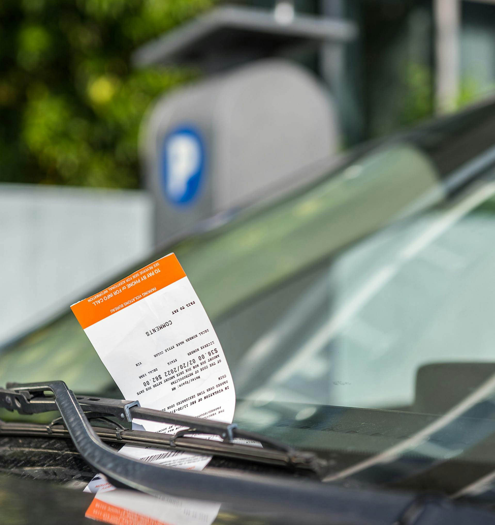 Ticket underneath someone's windshield wiper.