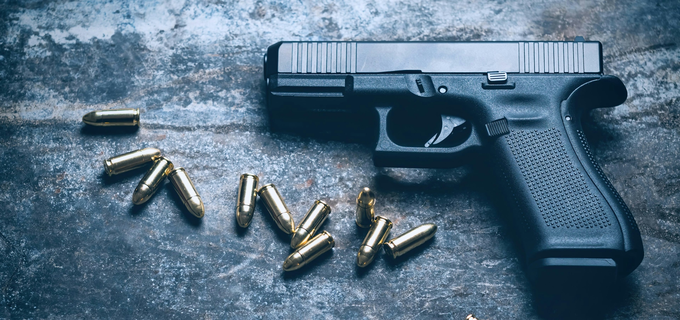 Pistol on Concrete with Bullets Next to it - Firearm Charges Banner