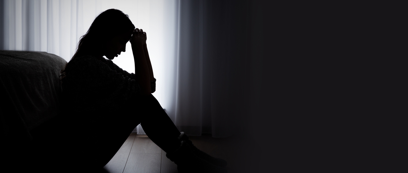 Silhouette of a woman sitting on the floor in despair.