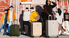 a woman standing next to two suitcases in front of a mural