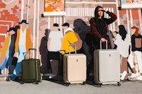 a woman standing next to two suitcases in front of a mural