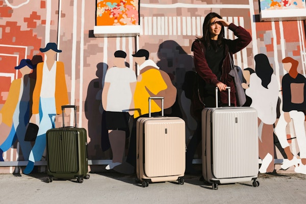 a woman standing next to two suitcases in front of a mural