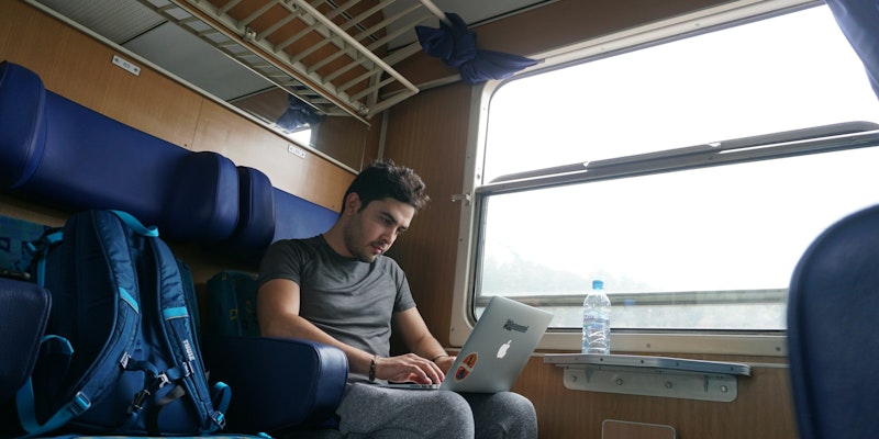 a man sitting on a train looking at his laptop a man sitting on a train looking at his laptop