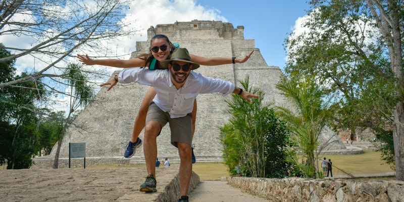 man in white t-shirt and brown shorts jumping on brown concrete pathway during daytime
