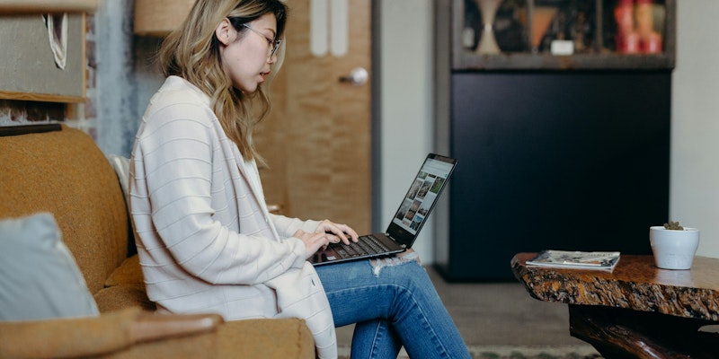 woman using laptop while sitting on sofa chair