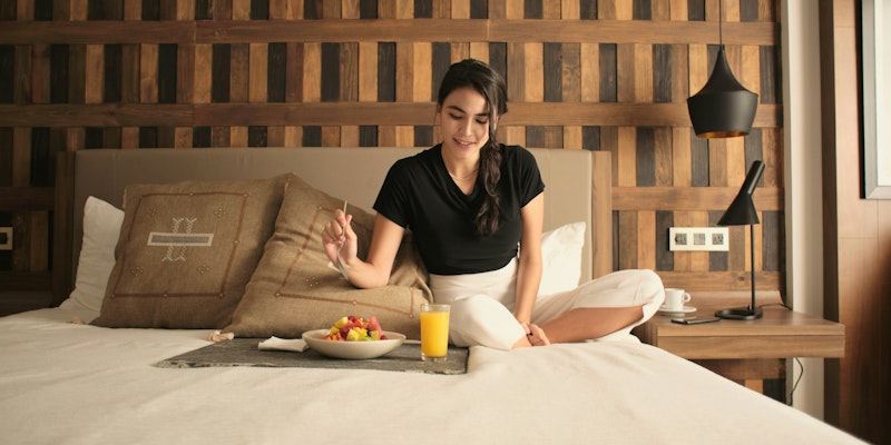 A woman sitting on a bed in a hotel room