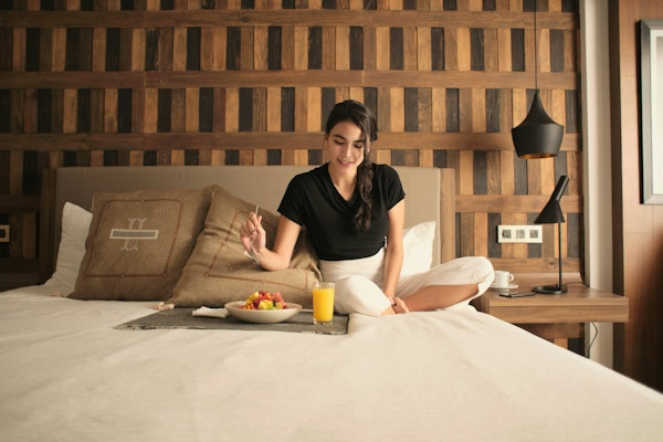 A woman sitting on a bed in a hotel room