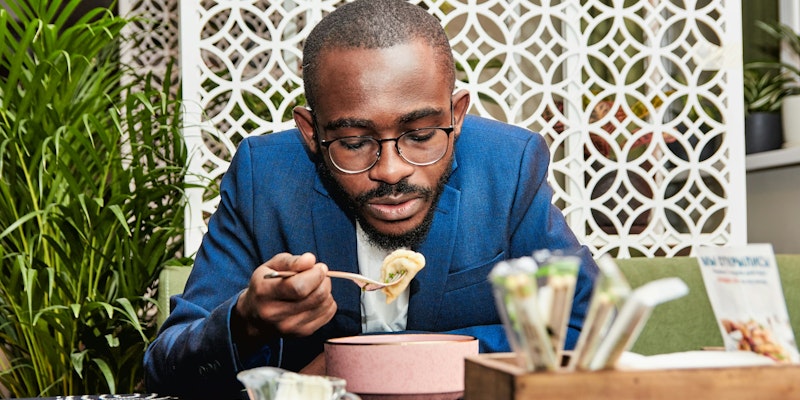 man in blue suit jacket holding white ceramic mug