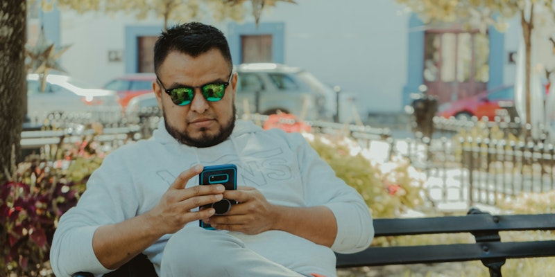 man in white crew neck t-shirt holding black smartphone