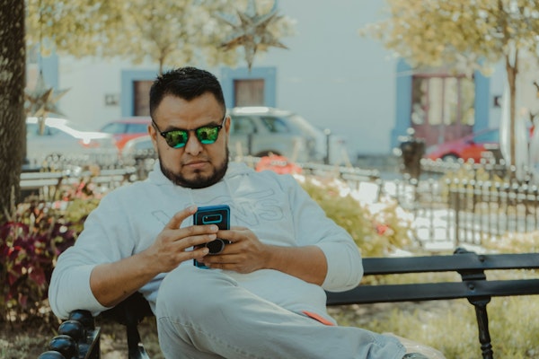 man in white crew neck t-shirt holding black smartphone