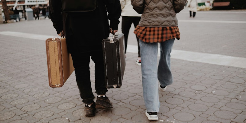 a man and a woman walking down a street with luggage