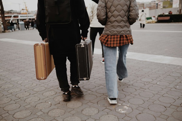 a man and a woman walking down a street with luggage