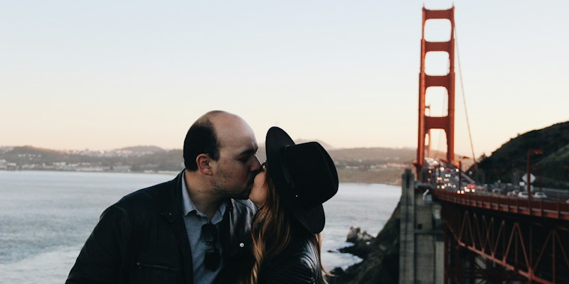 man and woman kissing beside Golden Gate Bridge during daytime
