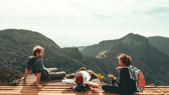 three people overlooking mountains