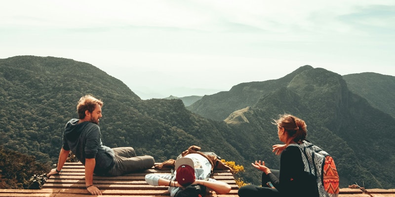 three people overlooking mountains