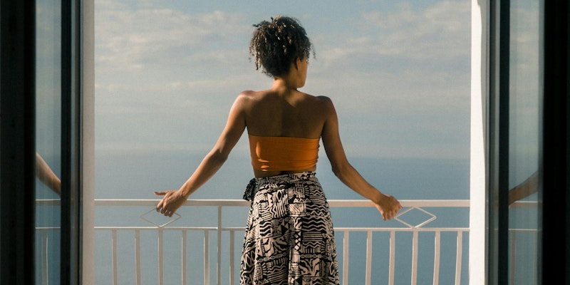 woman wearing orange tube and black skirt facing terrace