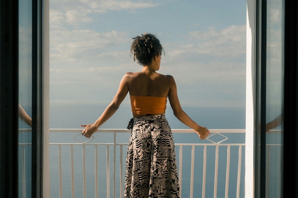 woman wearing orange tube and black skirt facing terrace