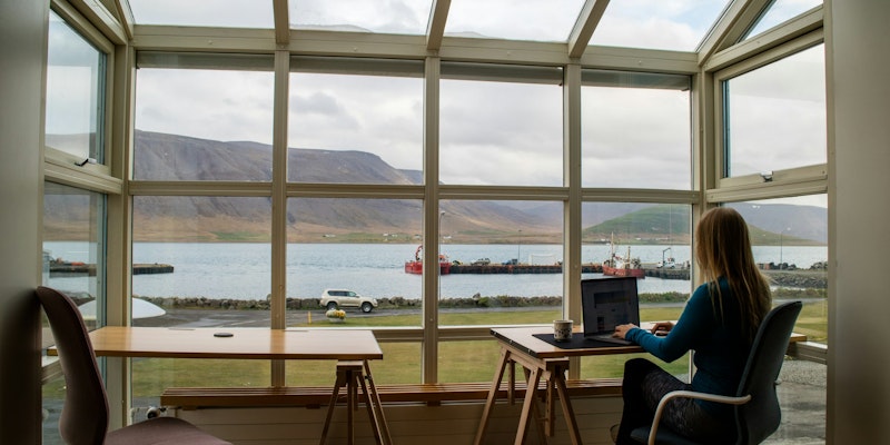 person in blue jacket sitting on brown wooden chair near brown wooden table during daytime