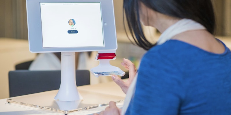 woman in blue long-sleeved shirt in front of turned on monitor