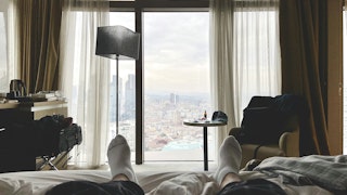 2 men lying on bed near window