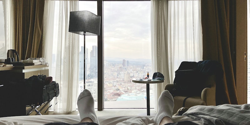 2 men lying on bed near window