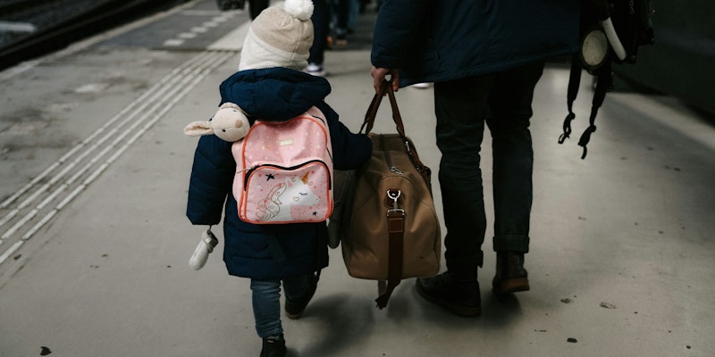 A child walks with a person holding luggage.