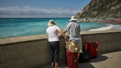 man and woman standing beside concrete seawall looking at beach