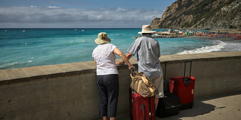 man and woman standing beside concrete seawall looking at beach