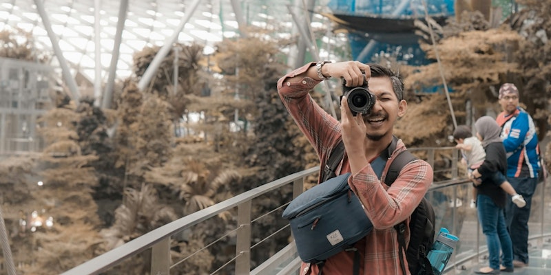 man in black and red backpack taking photo of trees during daytime