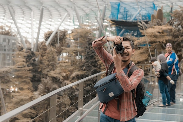 man in black and red backpack taking photo of trees during daytime